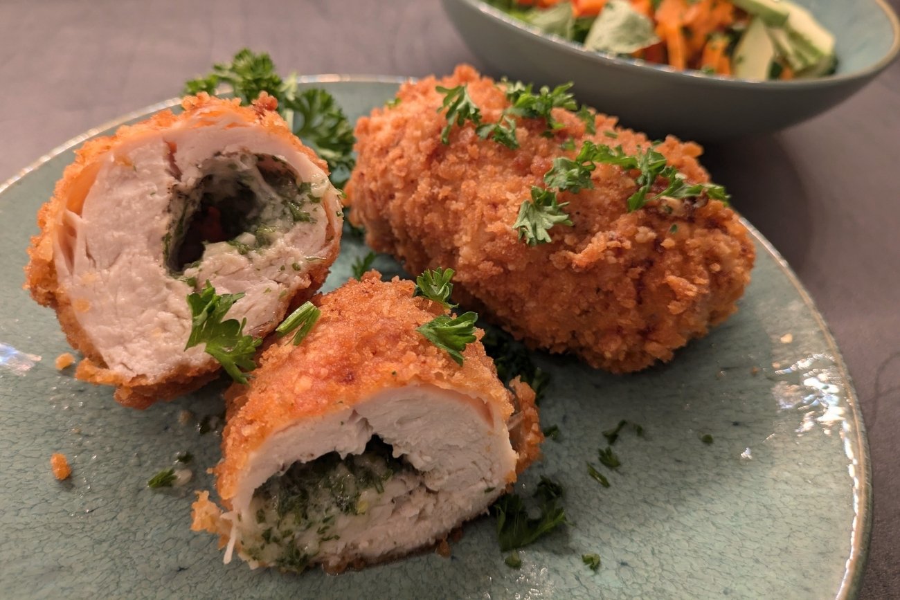 Chicken Kiev fertig gekocht. Paniertes Hähnchen mit Kräuterbutterfüllung - Originalrezept.